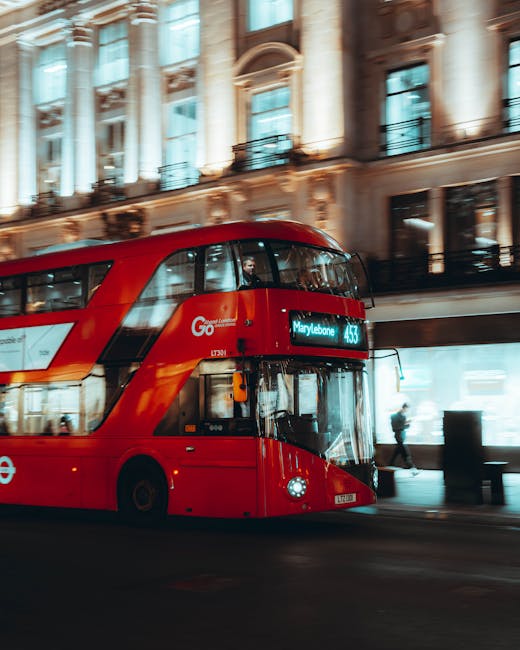 A red double-decker bus displaying the route to 'Marylebone' parked on a city street near a historic-looking building with ornate stone facades and large windows. The bus is part of the London public transportation system, which is often utilized during house removals and moving services in the Marylebone area. In the background, pedestrians walk along the sidewalk, and some are approaching or passing the bus. The scene is set during daylight with clear, bright conditions, highlighting the urban environment that [COMPANY_NAME], such as Man and Van Marylebone, navigates when assisting clients with furniture transport, packing, and home relocations in the vicinity.